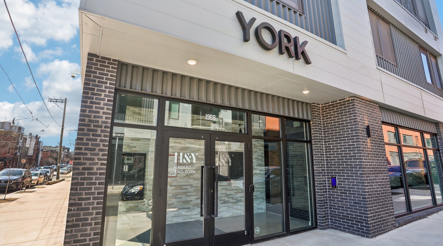 The exterior of Hagert and York Apartments in Philadelphia, PA, featuring glass doors and a modern facade.